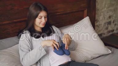 正在玩耍的准妈妈正在怀孕的肚子上踩着蓝色的<strong>小鞋子</strong>，微笑着躺在家里的阁楼上